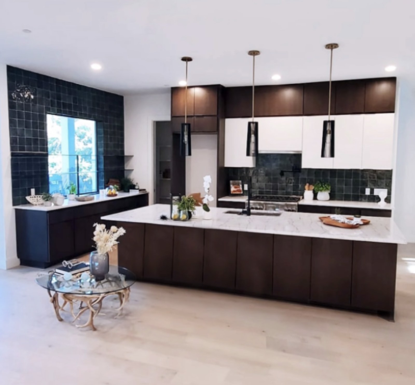 Modern kitchen with dark espresso cabinets, a marble waterfall island and deep green tile backsplash